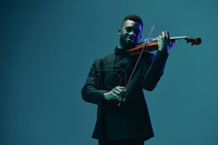 Foto de Elegante hombre de traje tocando el violín sobre fondo azul oscuro concepto de interpretación de música clásica - Imagen libre de derechos