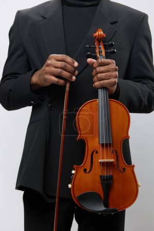 Photo for African American man holding violin in black suit standing in front of white background in studio portrait concept - Royalty Free Image