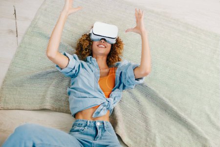 Foto de Mujer sonriente disfrutando del juego de realidad virtual en el sofá en casa - Imagen libre de derechos