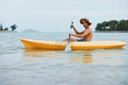 Téléchargez les photos : Plaisir d'été Kayak sur une plage tropicale : Homme asiatique actif appréciant les sports nautiques et les vacances de loisirs - en image libre de droit