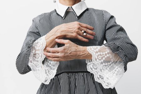 Téléchargez les photos : Femme plus âgée élégante en robe rayée avec des détails en dentelle et col blanc, debout gracieusement - en image libre de droit