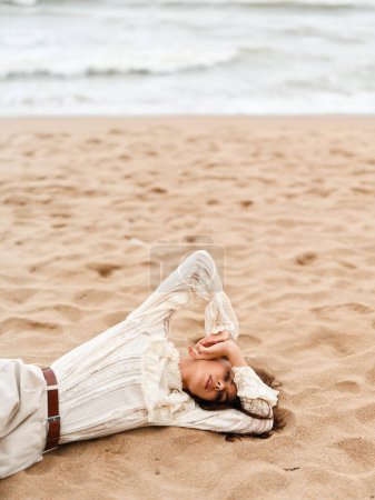Téléchargez les photos : Summer Bliss : Une jeune femme jouissant d'une vue magnifique sur le littoral, se sentant sereine et rayonnante de beauté dans une robe blanche sous le ciel ensoleillé - en image libre de droit