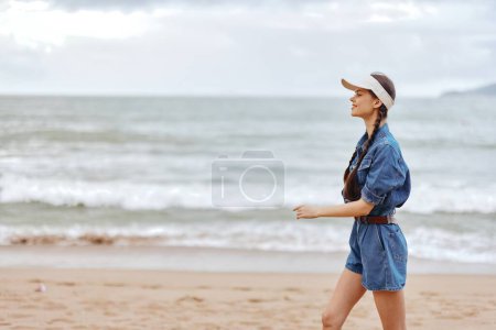 Téléchargez les photos : Escapade estivale sereine : Une belle jeune femme profite de la liberté et de la détente de vacances ensoleillées à la plage. - en image libre de droit
