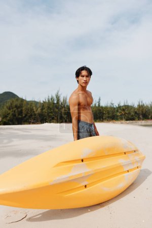 Photo for Happy Asian Man Enjoying Kayaking Adventure on a Tropical Beach - Royalty Free Image