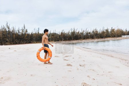 Bademeister am Strand: Ein Asiate, der Retter des Sommers, umarmt Sicherheit und Freude inmitten der Wellen des Blauen Ozeans.