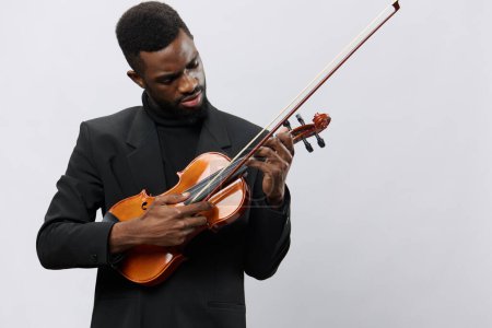 Téléchargez les photos : Un talentueux Afro-Américain en costume noir jouant du violon sur un fond blanc propre - en image libre de droit