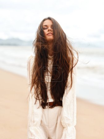 Foto de Belleza de moda de verano: Joven y atractiva dama de vestido blanco, relajante en la playa, disfrutando del sol y el océano - Imagen libre de derechos
