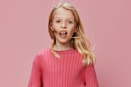 Foto de Colegiala feliz con un traje rosa elegante y una gran sonrisa, posando con confianza en un estudio de fotografía Su rostro expresivo y expresión alegre reflejan la alegría pura de la infancia, mientras que el vibrante - Imagen libre de derechos