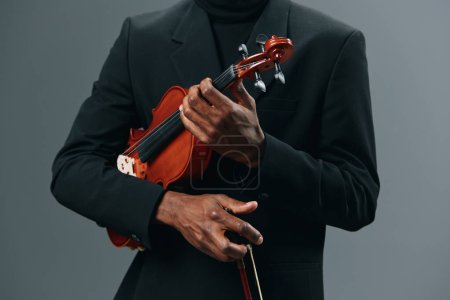 Foto de Hombre afroamericano con elegante cuello alto y traje negro posando con violín en la mano - Imagen libre de derechos