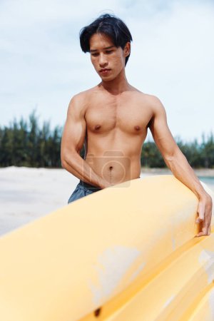 Kayak tropical : un homme asiatique heureux profitant d'une aventure sur la plage