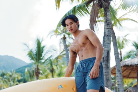 Téléchargez les photos : Serene Summer Kayak : Un Asiatique Heureux Profitant d'une aventure de canoë-kayak sur une plage tropicale - en image libre de droit