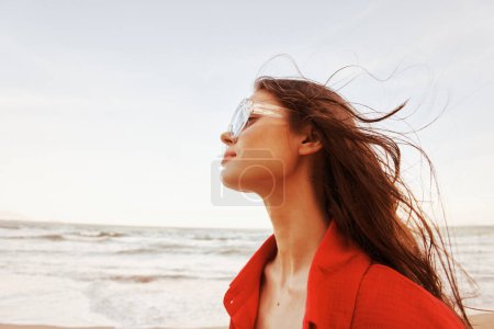 Téléchargez les photos : Femme souriante dans les lunettes de soleil à la mode, Faire place à la liberté : Un portrait coloré à la plage - en image libre de droit
