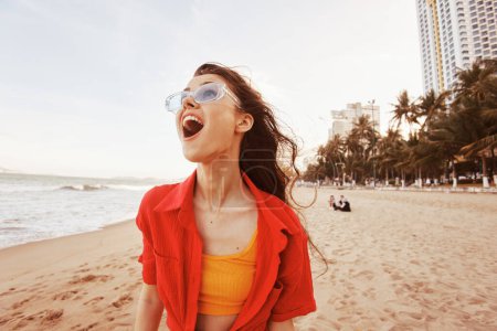 Téléchargez les photos : Femme souriante profitant de vacances sans soucis au coucher du soleil sur une plage colorée : un portrait vibrant de joie et de liberté - en image libre de droit