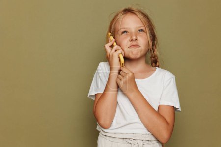 Photo for Young girl talking on smartphone with concerned expression. - Royalty Free Image