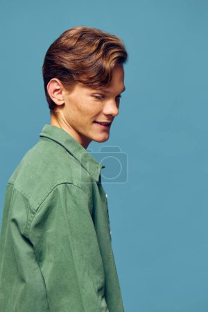 Foto de Hombre joven con camisa verde contra fondo azul - Imagen libre de derechos