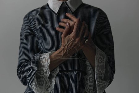 Photo for Elderly woman in a striped dress posing with hands on chest and looking at camera portrait - Royalty Free Image
