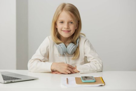 Téléchargez les photos : Fille souriante Apprendre avec ordinateur portable Une belle adolescente caucasienne s'assoit à son bureau à la maison, absorbée par elearning Avec un ordinateur portable en face d'elle, elle s'engage joyeusement dans l'éducation en ligne, dactylographier et - en image libre de droit