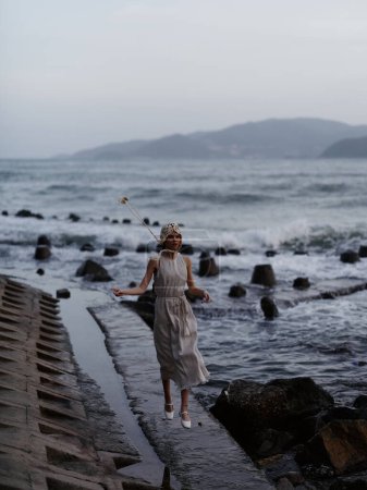 Foto de Soledad junto al mar: una joven disfrutando de una serena caminata al atardecer en una playa remota - Imagen libre de derechos