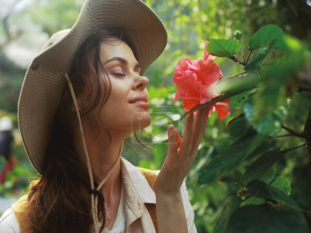 Téléchargez les photos : Une femme portant un chapeau et tenant une fleur dans sa main tout en regardant la caméra - en image libre de droit