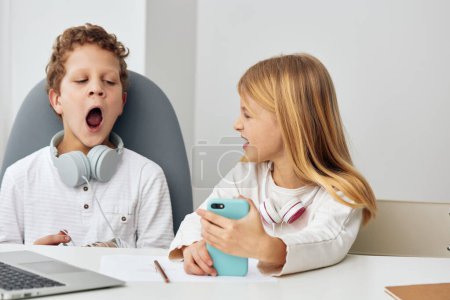 Photo for Happy Caucasian Boy and Girl Learning Online with Laptops at Home, Engaged in ELearning Activities They are Sitting in a Cozy Living Room, Wearing Headphones, and Concentrating on their Studies - Royalty Free Image
