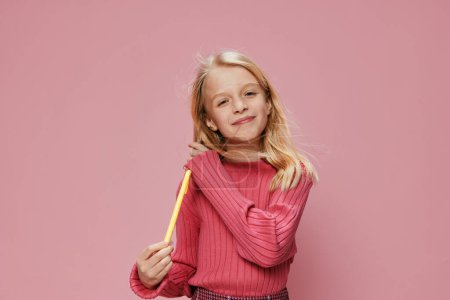 Foto de Linda colegiala con una sonrisa alegre sosteniendo una piruleta rosa en un elegante estudio, expresando felicidad y emoción su hermosa cara caucásica irradia alegría infantil contra una diversión y colorido - Imagen libre de derechos
