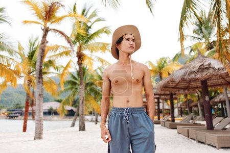 Foto de Sonriente asiático hombre en tropical playa disfrutando de vacaciones de verano - Imagen libre de derechos