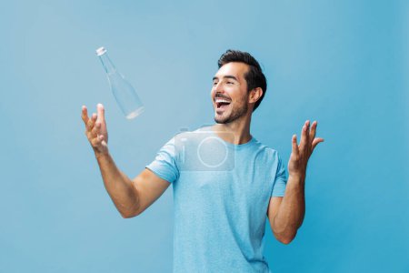 Photo for Lifestyle man cheerful isolated exercise background smile drink happy sexy blue studio bottle attractive beauty fresh portrait water healthy holding hand t-shirt sport drinking - Royalty Free Image