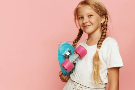 Téléchargez les photos : Adorable petite fille patinant avec confiance sur un tableau rose Penny - Concept de mode de vie actif - en image libre de droit