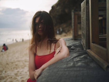 Téléchargez les photos : Jeune femme avec un regard triste regarde dans la caméra avec portrait cheveux lâches sur la plage lors d'un voyage vacances d'été en mer. Photo de haute qualité - en image libre de droit