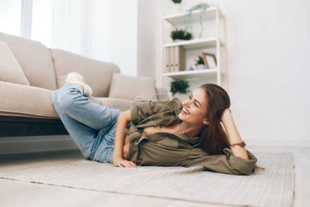 Téléchargez les photos : Appartement confortable : Allongé sur un canapé moderne, femme heureuse se détendre dans un salon paisible - en image libre de droit