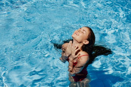 Photo for Happy woman swimming in the pool in red swimsuit with loose long hair in the sunshine, skin protection with sunscreen, concept of relaxing on vacation. High quality photo - Royalty Free Image