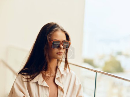 Foto de Modelo femenino con estilo posando con gafas de sol en Sunny City Street: Belleza de moda en el estilo de vida urbano casual - Imagen libre de derechos
