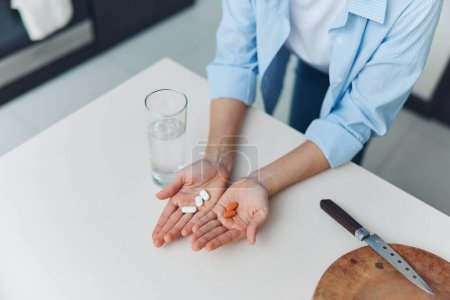 Photo for Female holding pills and glass of water with knife on white table concept of healthcare and medication - Royalty Free Image