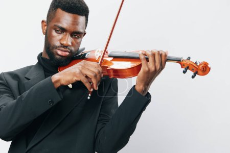 Foto de Hombre afroamericano talentoso en un traje tocando el violín con pasión sobre un fondo blanco - Imagen libre de derechos