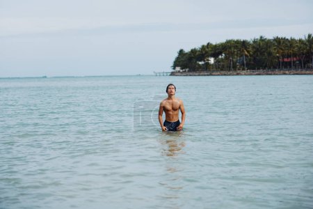 Téléchargez les photos : Un nageur jouissant de la félicité tropicale : Océan bleu, plage ensoleillée et amis joyeux - en image libre de droit