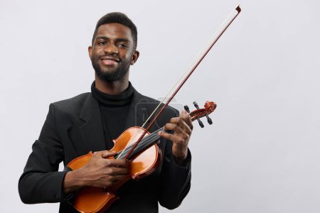 Téléchargez les photos : Musicien afro-américain professionnel en costume formel tenant le violon sur fond blanc pour la publicité liée à la musique - en image libre de droit