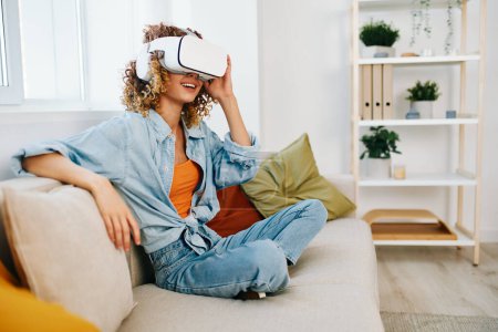Foto de Emoción de la realidad virtual: Mujer sonriente disfrutando de un juego futurista de realidad virtual en la comodidad de su hogar - Imagen libre de derechos