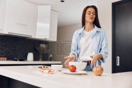 Téléchargez les photos : Une femme prépare un repas sain avec des légumes frais dans un cadre de cuisine confortable - en image libre de droit