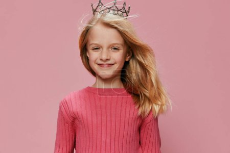 Téléchargez les photos : Petite fille mignonne avec une couronne de princesse rose célébrant son anniversaire dans une fête de carnaval joyeuse et magique - en image libre de droit