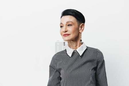 Photo for Portrait of an elegant senior woman in a stylish black and white striped shirt against a plain background - Royalty Free Image