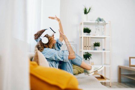 Foto de Mujer sonriente disfrutando del juego de realidad virtual en casa: entretenimiento digital futurista en la sala de estar moderna - Imagen libre de derechos