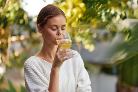 Photo for Happy Woman Enjoying Refreshing Kombucha Drink in Sunny Nature Healthy Lifestyle and Wellness Concept Detox and Antioxidant Boost Female Holding a Glass of Organic Fruit Infused Beverage - Royalty Free Image