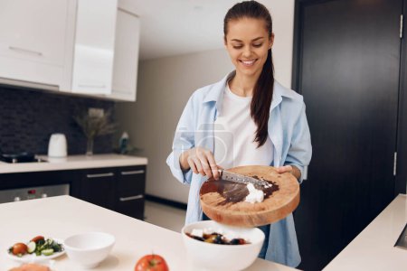 Photo for Woman preparing a healthy dessert with a bowl of fruit and a bowl of brownies in the kitchen - Royalty Free Image