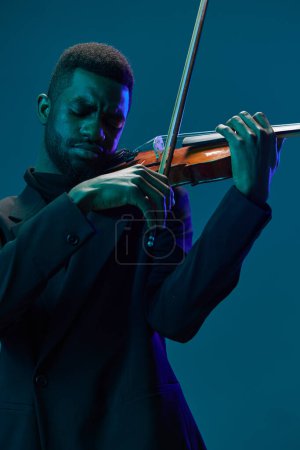 Téléchargez les photos : Violoniste professionnel en costume performant sur scène avec éclairage bleu en arrière-plan sur fond bleu foncé - en image libre de droit