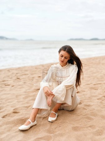 Photo for Beach Beauty: Young Woman, Stylish and Attractive, Standing on the Sand, Gazing at the Ocean, Enjoying Summer Vacation. - Royalty Free Image