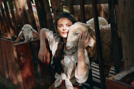Téléchargez les photos : Une femme tient un mouton devant une clôture avec d'autres moutons en arrière-plan - en image libre de droit