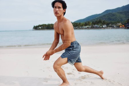 Photo for Muscular Asian Athlete Running on the Beach, Fueling Fitness in Lifestyle - Royalty Free Image
