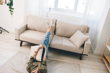 Téléchargez les photos : Détente sur un canapé moderne confortable : une femme heureuse profitant de vacances paisibles dans un appartement confortable - en image libre de droit