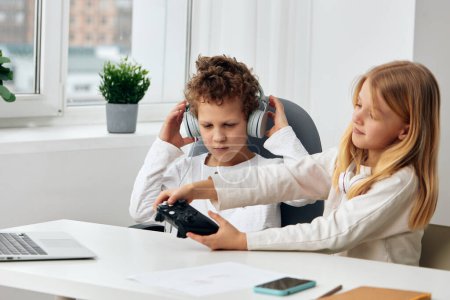 Foto de Niños caucásicos felices estudiando en línea en casa con computadoras portátiles y tabletas, participando en actividades de ELearning - Imagen libre de derechos