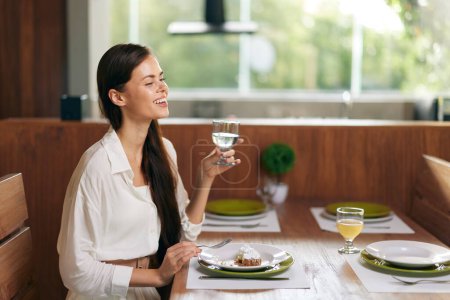 Foto de Cena romántica cita mujer disfrutando de comida casera con sonrisa extática, mesa con decoraciones de moda y delicioso pastel - Imagen libre de derechos